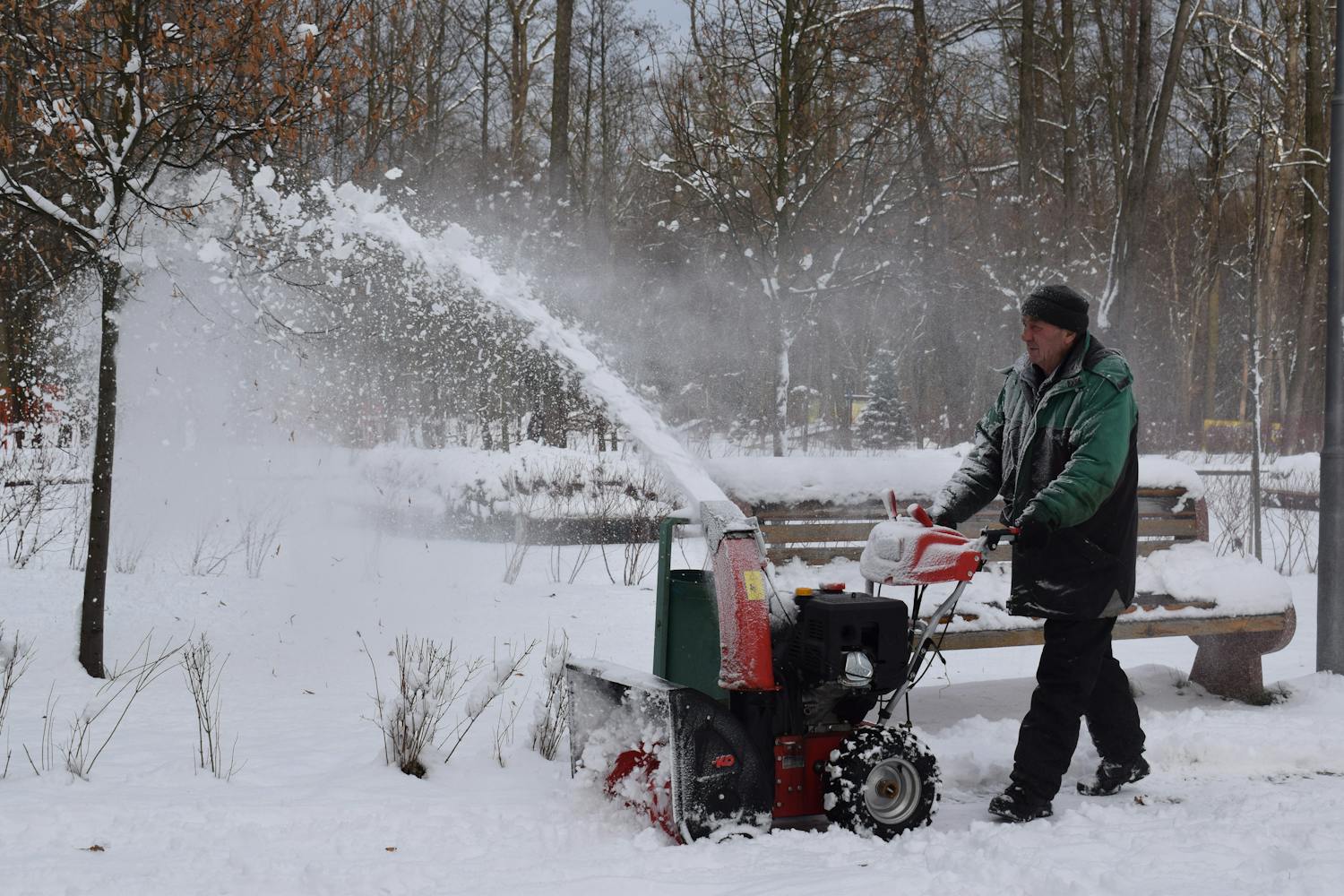 Man in Green Jacket Using Snow Blower<br />
